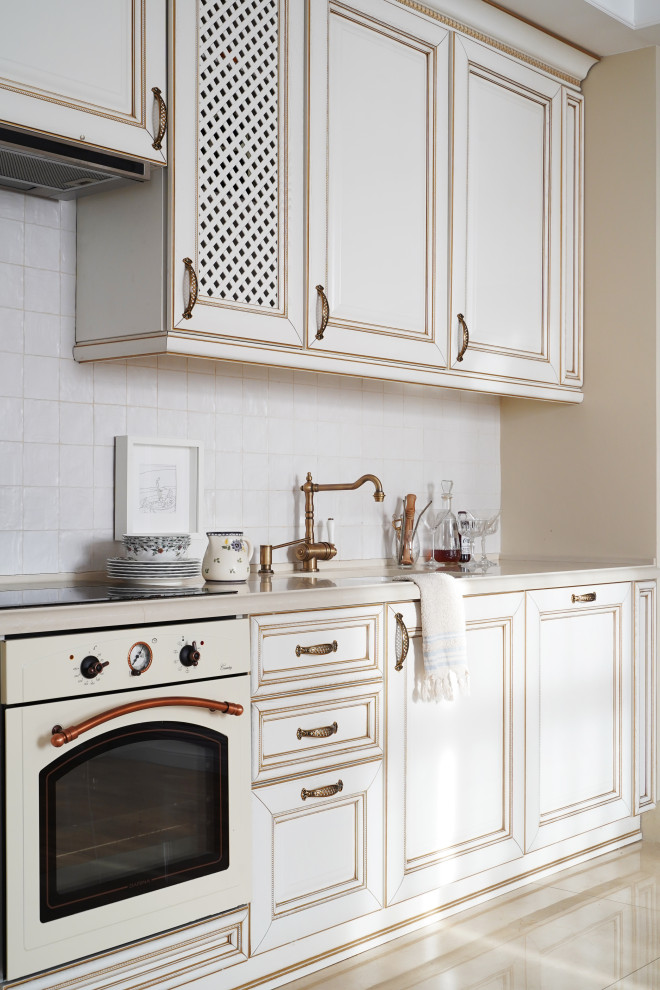 This is an example of a small traditional single-wall eat-in kitchen in Moscow with a farmhouse sink, beaded inset cabinets, white cabinets, quartz benchtops, white splashback, cement tile splashback, white appliances, porcelain floors, no island, beige floor, beige benchtop and exposed beam.