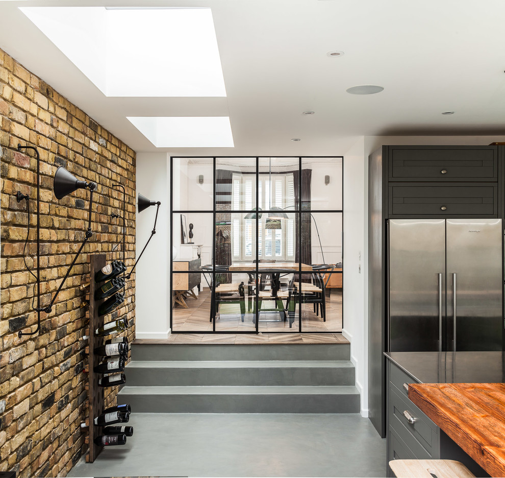 This is an example of a contemporary kitchen in London with a double-bowl sink, medium wood cabinets, wood benchtops, stainless steel appliances and with island.