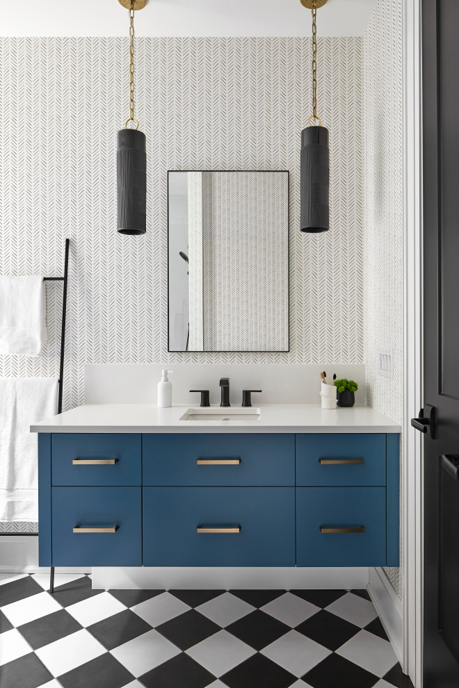 Inspiration for a mid-sized contemporary kids bathroom in Toronto with flat-panel cabinets, blue cabinets, a drop-in tub, a shower/bathtub combo, a one-piece toilet, white tile, porcelain tile, white walls, porcelain floors, an undermount sink, engineered quartz benchtops, black floor, a hinged shower door, white benchtops, a single vanity, a floating vanity and wallpaper.