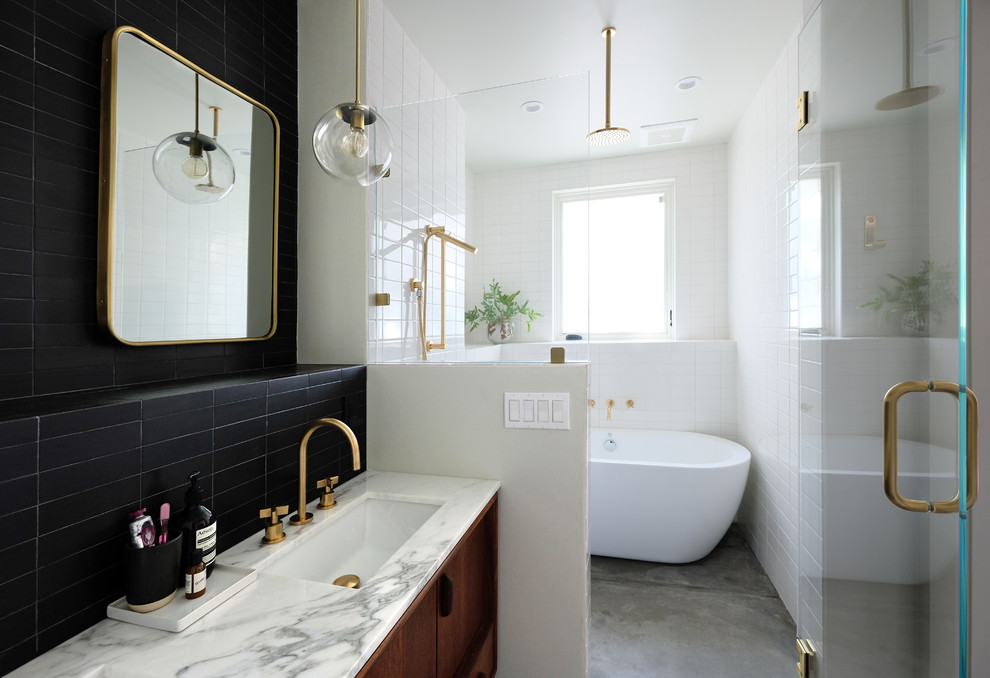 Photo of a mid-sized eclectic master wet room bathroom in San Francisco with medium wood cabinets, a freestanding tub, a one-piece toilet, black and white tile, ceramic tile, white walls, concrete floors, an undermount sink, marble benchtops, grey floor, a hinged shower door and flat-panel cabinets.
