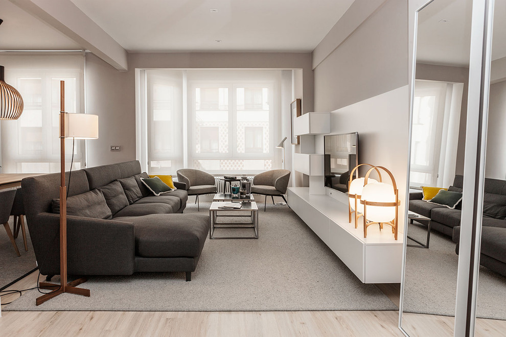 This is an example of a mid-sized contemporary formal open concept living room in Bilbao with grey walls, light hardwood floors, no fireplace and a wall-mounted tv.
