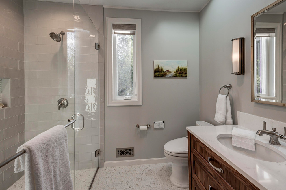 This is an example of a mid-sized traditional bathroom in Seattle with shaker cabinets, dark wood cabinets, a curbless shower, a one-piece toilet, gray tile, ceramic tile, grey walls, cement tiles, an undermount sink, engineered quartz benchtops, white floor, a hinged shower door, white benchtops, a niche, a single vanity and a freestanding vanity.