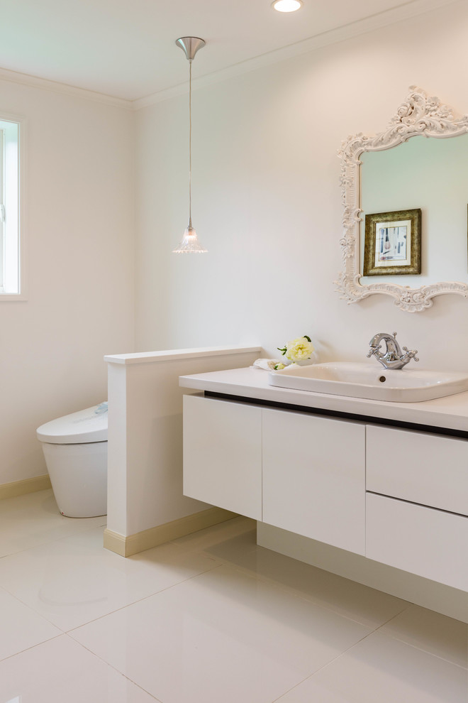 Photo of a contemporary powder room in Other with flat-panel cabinets, white cabinets, white walls, a drop-in sink and white floor.