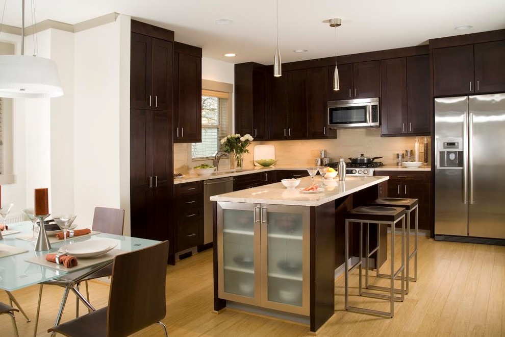 Example of a mid-sized transitional l-shaped light wood floor eat-in kitchen design in New York with an undermount sink, shaker cabinets, dark wood cabinets, quartzite countertops, white backsplash, glass sheet backsplash, stainless steel appliances and an island