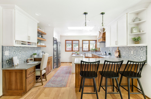 Two-tone kitchen with white RTA cabinets, wood base cabinets, patterned blue backsplash, and a peninsula with black bar stools.
