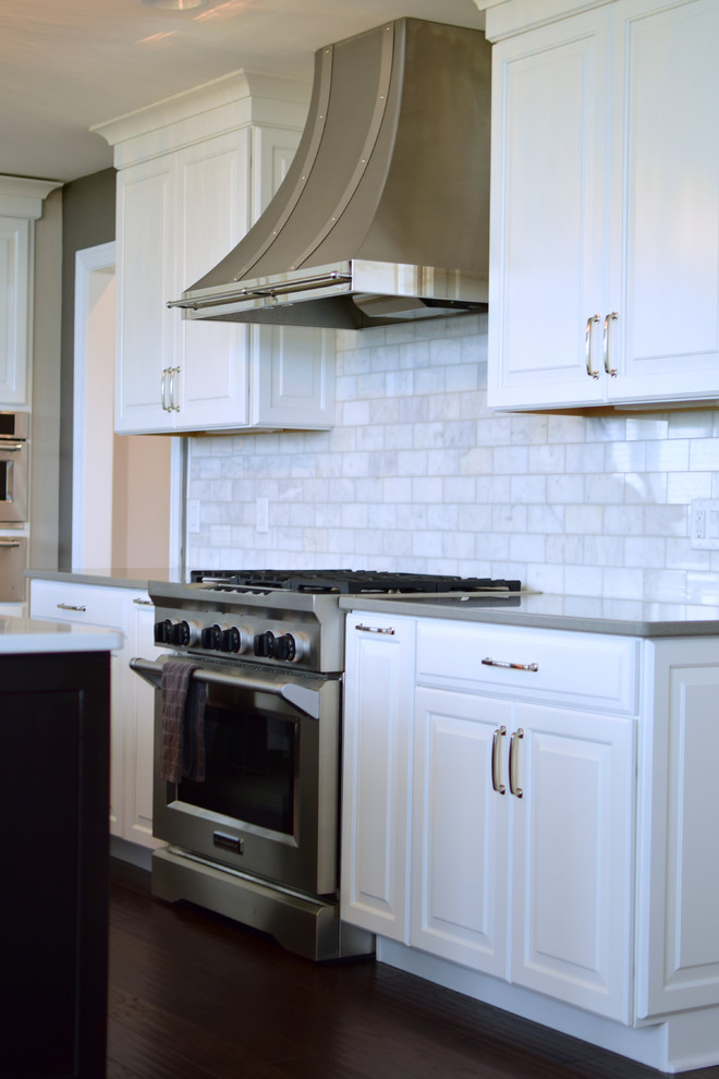 Inspiration for a large transitional l-shaped medium tone wood floor and brown floor eat-in kitchen remodel with a farmhouse sink, shaker cabinets, white cabinets, quartz countertops, white backsplash, marble backsplash, stainless steel appliances and two islands
