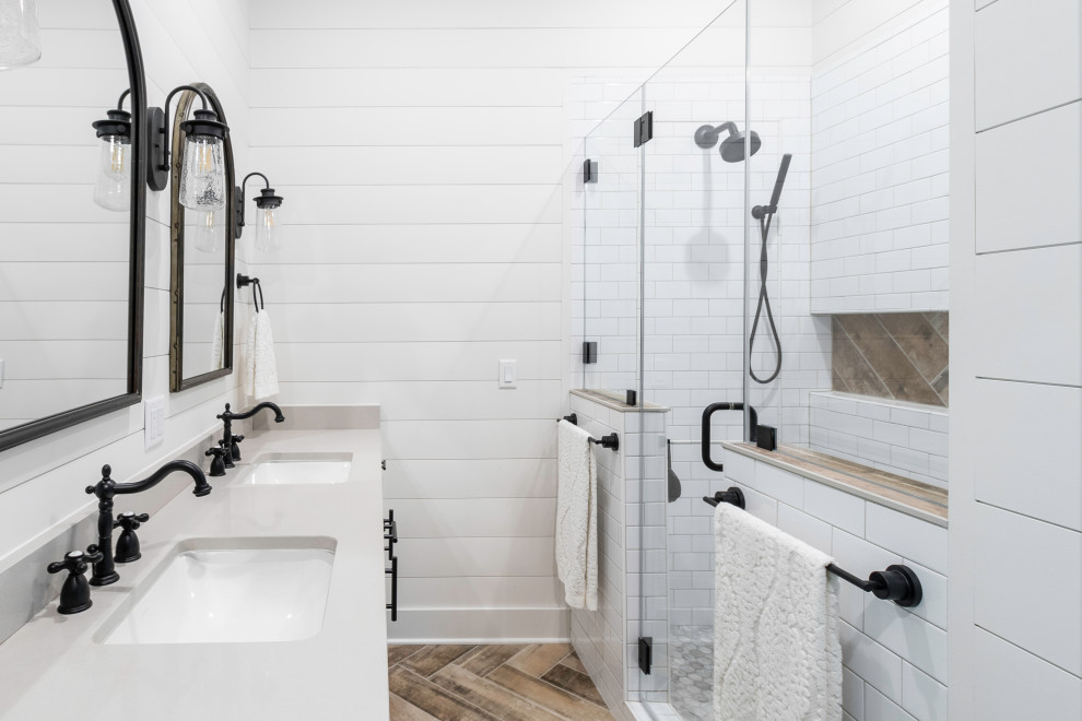Foto på ett mellanstort lantligt grå en-suite badrum, med skåp i shakerstil, vita skåp, en dusch i en alkov, vit kakel, tunnelbanekakel, vita väggar, målat trägolv, ett undermonterad handfat, bänkskiva i kvarts, brunt golv och dusch med gångjärnsdörr