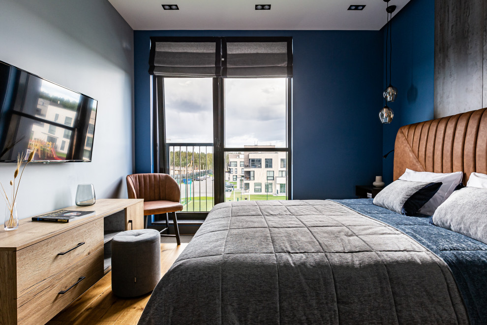 Aménagement d'une chambre parentale contemporaine en bois de taille moyenne avec un mur bleu, sol en stratifié et un sol marron.