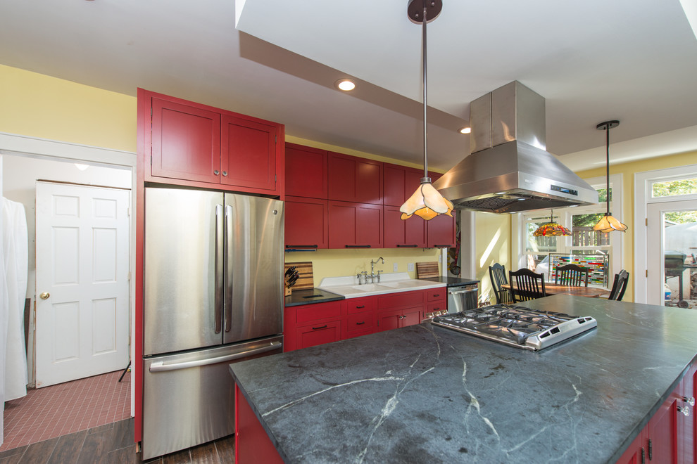 Design ideas for a mid-sized contemporary galley eat-in kitchen in Other with a double-bowl sink, raised-panel cabinets, red cabinets, soapstone benchtops, stainless steel appliances, dark hardwood floors, with island and brown floor.