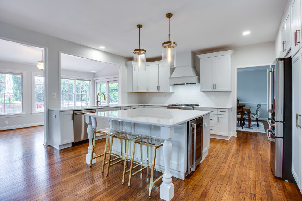 This is an example of a medium sized classic l-shaped kitchen in DC Metro with a submerged sink, recessed-panel cabinets, white cabinets, engineered stone countertops, stainless steel appliances, an island and white worktops.
