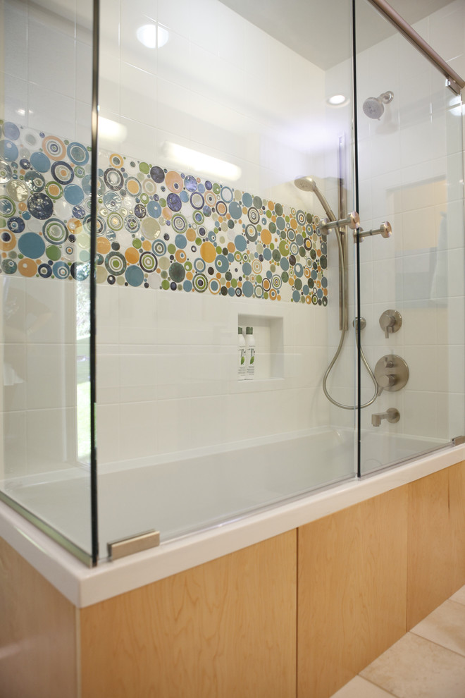 Photo of a mid-sized contemporary master bathroom in Minneapolis with medium wood cabinets, a shower/bathtub combo, multi-coloured tile, mosaic tile, a vessel sink, flat-panel cabinets, a one-piece toilet, white walls, ceramic floors and a drop-in tub.