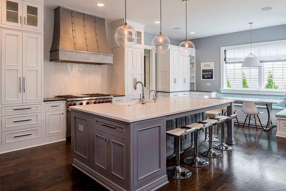 This is an example of a mid-sized transitional single-wall open plan kitchen in Chicago with a farmhouse sink, recessed-panel cabinets, white cabinets, quartz benchtops, white splashback, glass tile splashback, stainless steel appliances, medium hardwood floors and with island.