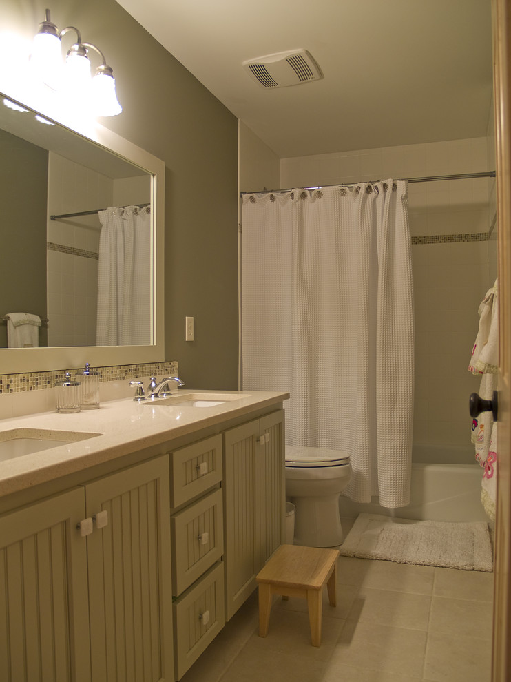 Photo of a mid-sized arts and crafts 3/4 bathroom in Minneapolis with recessed-panel cabinets, grey cabinets, an alcove tub, a shower/bathtub combo, a two-piece toilet, grey walls, porcelain floors, an undermount sink, engineered quartz benchtops, beige floor, a shower curtain and white benchtops.