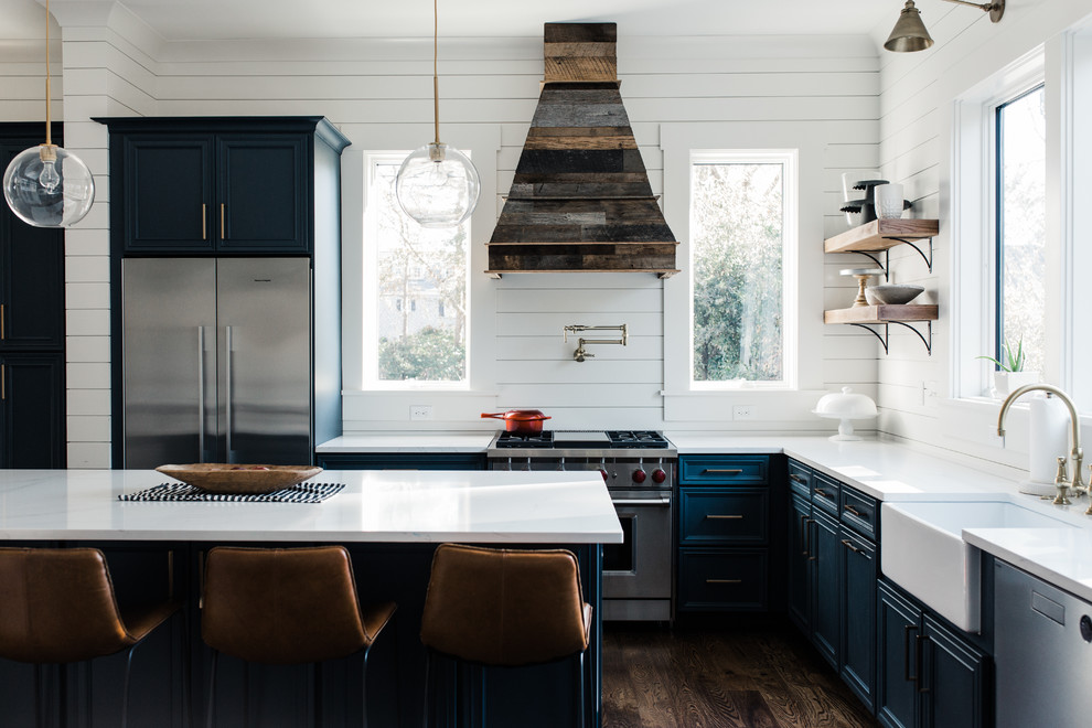 Design ideas for a beach style l-shaped kitchen in Charleston with a farmhouse sink, recessed-panel cabinets, blue cabinets, white splashback, stainless steel appliances, dark hardwood floors and with island.