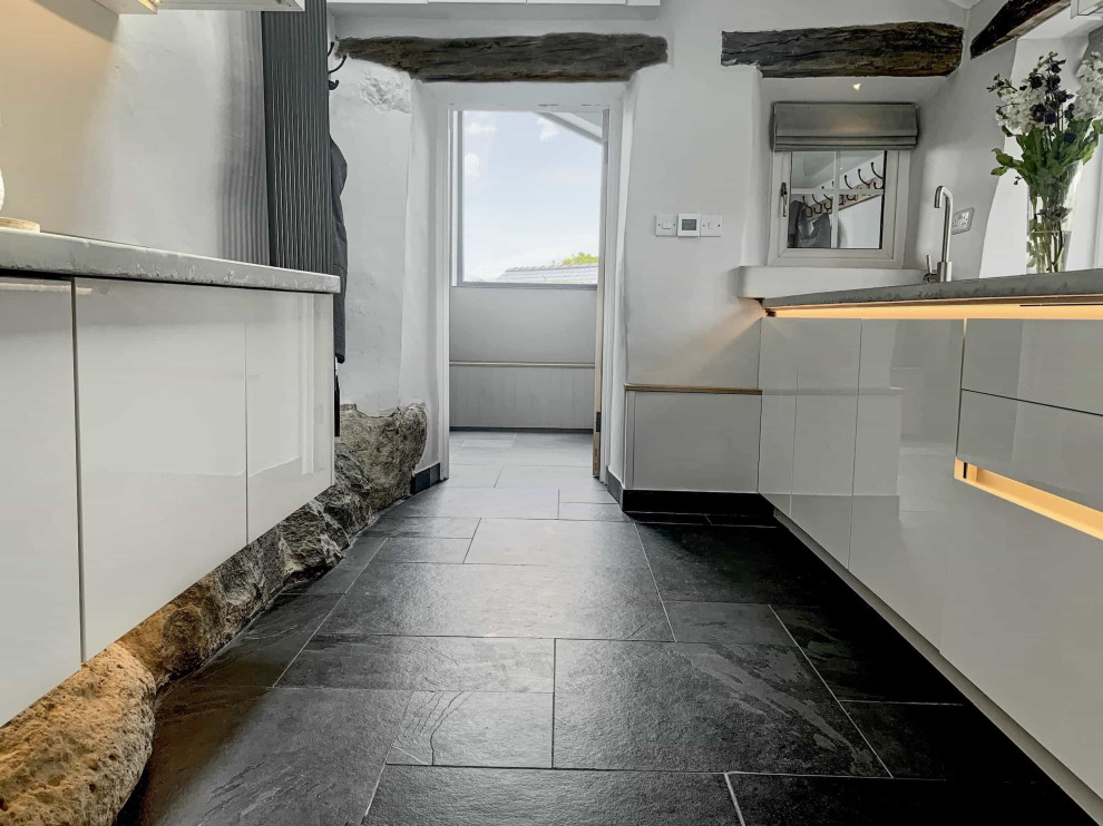 Exempel på ett mellanstort modernt grå grått kök, med en enkel diskho, släta luckor, vita skåp, bänkskiva i betong, grått stänkskydd, stänkskydd i cementkakel, svarta vitvaror, skiffergolv och svart golv