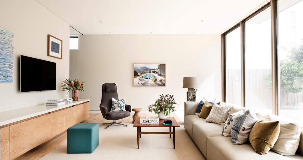 Photo of a living room in Sydney with beige walls, light hardwood floors and a wall-mounted tv.