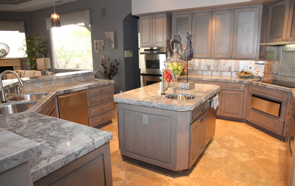 This is an example of a large transitional u-shaped kitchen in Phoenix with an undermount sink, brown cabinets, stainless steel appliances, travertine floors, multiple islands and beige floor.