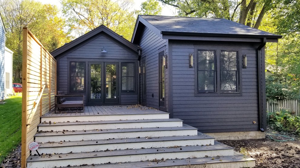 This is an example of a small country one-storey black house exterior in Chicago with vinyl siding, a gable roof and a shingle roof.