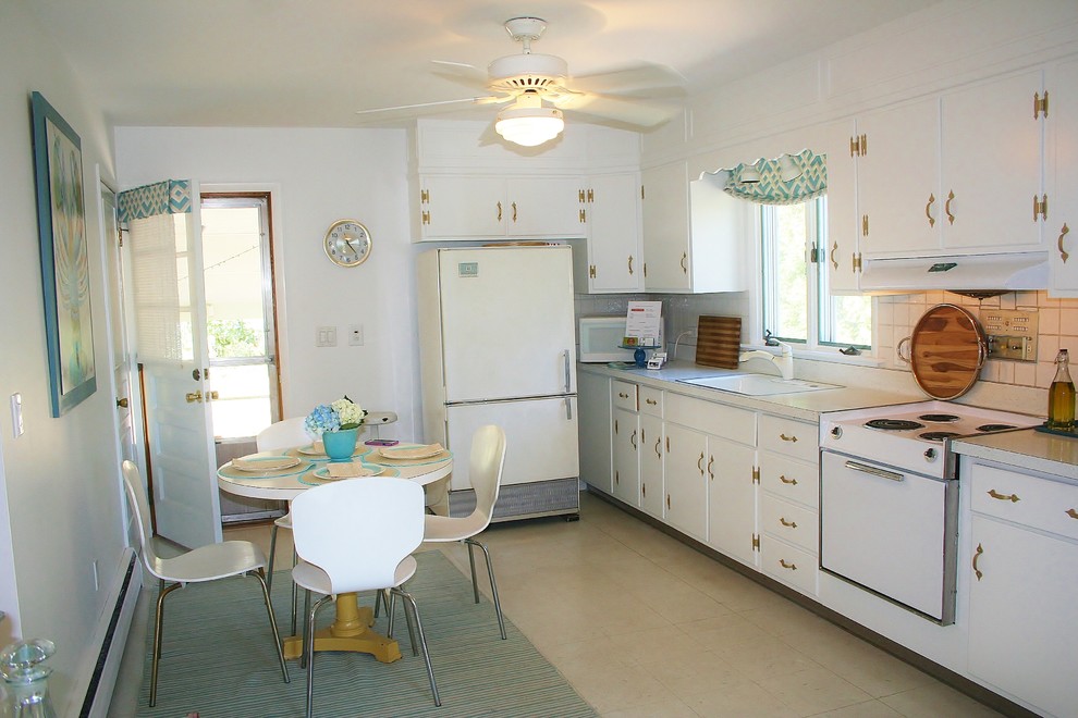 Example of a small transitional single-wall linoleum floor enclosed kitchen design in Bridgeport with a drop-in sink, flat-panel cabinets, white cabinets, laminate countertops, white backsplash, ceramic backsplash and white appliances