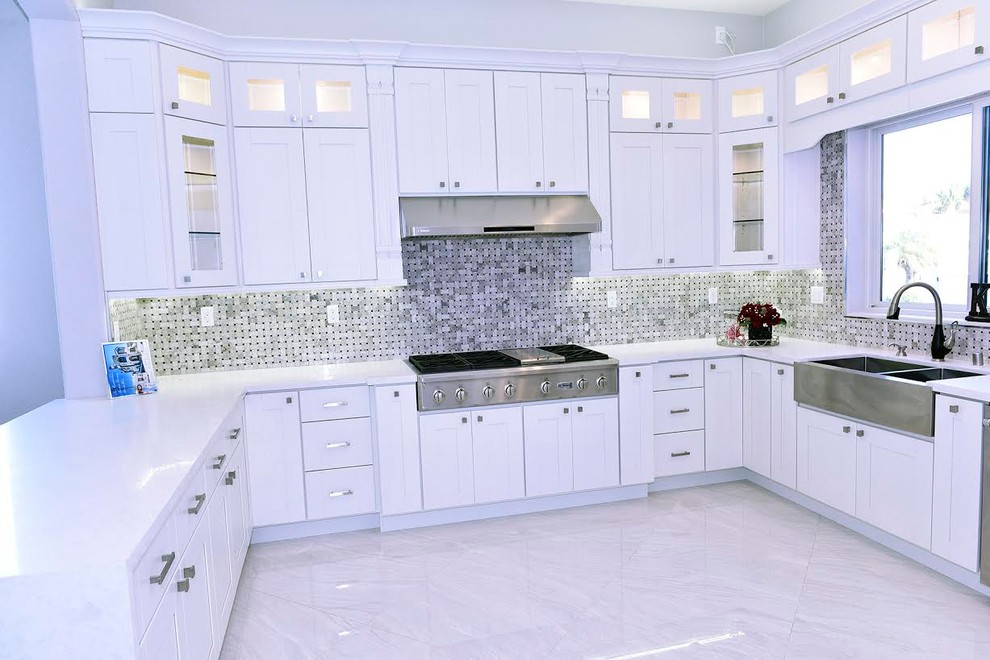 Large contemporary u-shaped open plan kitchen in Orange County with a farmhouse sink, shaker cabinets, white cabinets, quartzite benchtops, metallic splashback, mosaic tile splashback, stainless steel appliances, marble floors, a peninsula and white floor.