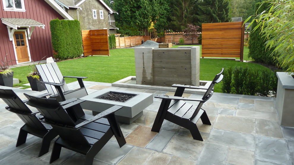 Inspiration for a mid-sized arts and crafts backyard patio in Vancouver with a fire feature, natural stone pavers and a roof extension.