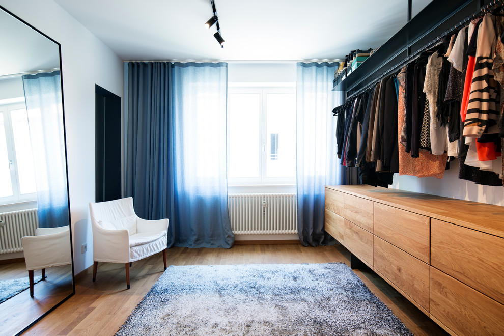 Inspiration for a mid-sized contemporary gender-neutral dressing room in Munich with flat-panel cabinets, medium wood cabinets, medium hardwood floors and brown floor.