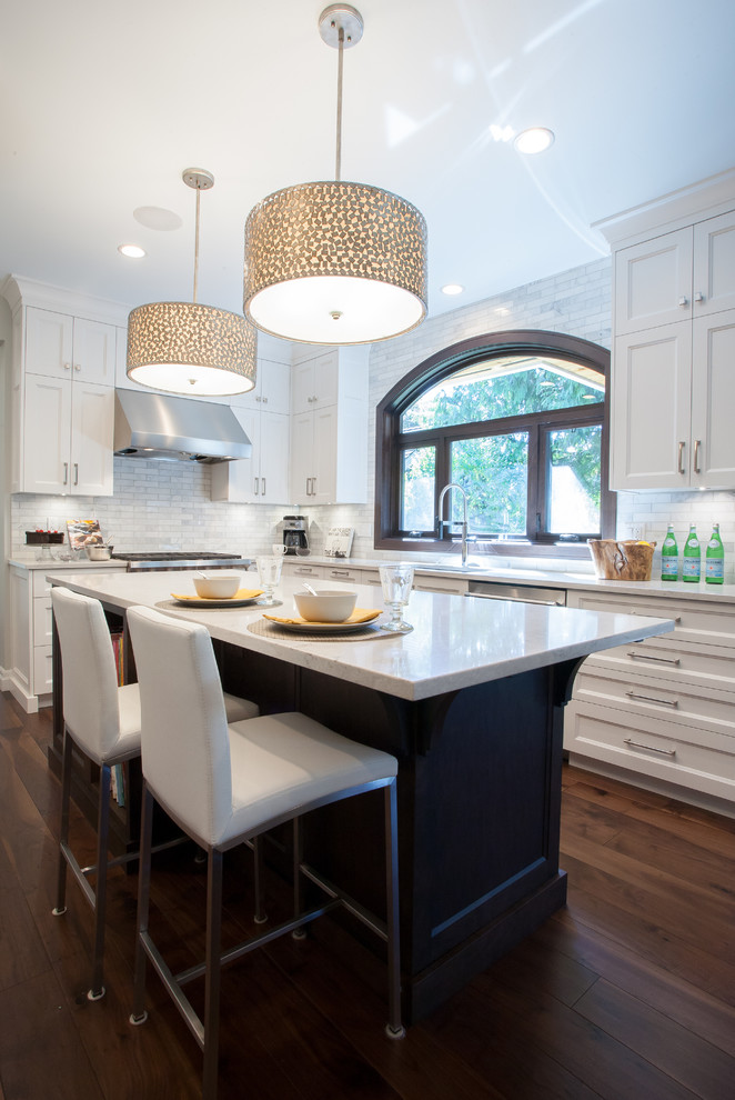 Photo of a large transitional l-shaped kitchen in Vancouver with an undermount sink, shaker cabinets, white cabinets, marble benchtops, white splashback, stone tile splashback, stainless steel appliances, dark hardwood floors and with island.
