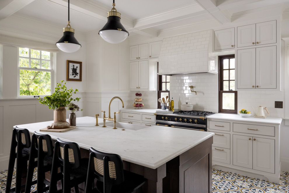 Large arts and crafts galley separate kitchen in Seattle with white cabinets, granite benchtops, white splashback, ceramic splashback, black appliances, ceramic floors, with island, white benchtop, a farmhouse sink, coffered, beaded inset cabinets and multi-coloured floor.