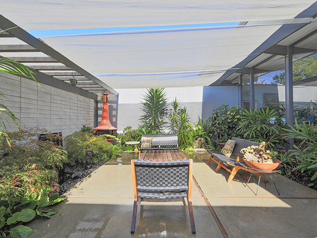 Inspiration for a mid-sized midcentury courtyard patio in Orange County with concrete pavers and an awning.