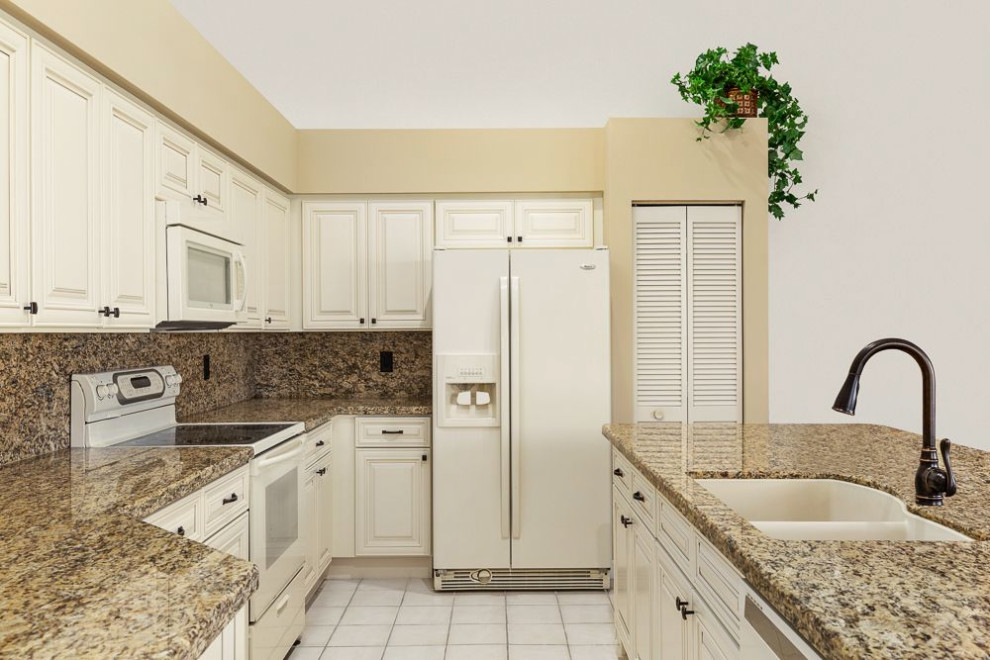 Mid-sized traditional l-shaped eat-in kitchen in Miami with a drop-in sink, raised-panel cabinets, beige cabinets, granite benchtops, yellow splashback, granite splashback, white appliances, ceramic floors, with island and yellow benchtop.