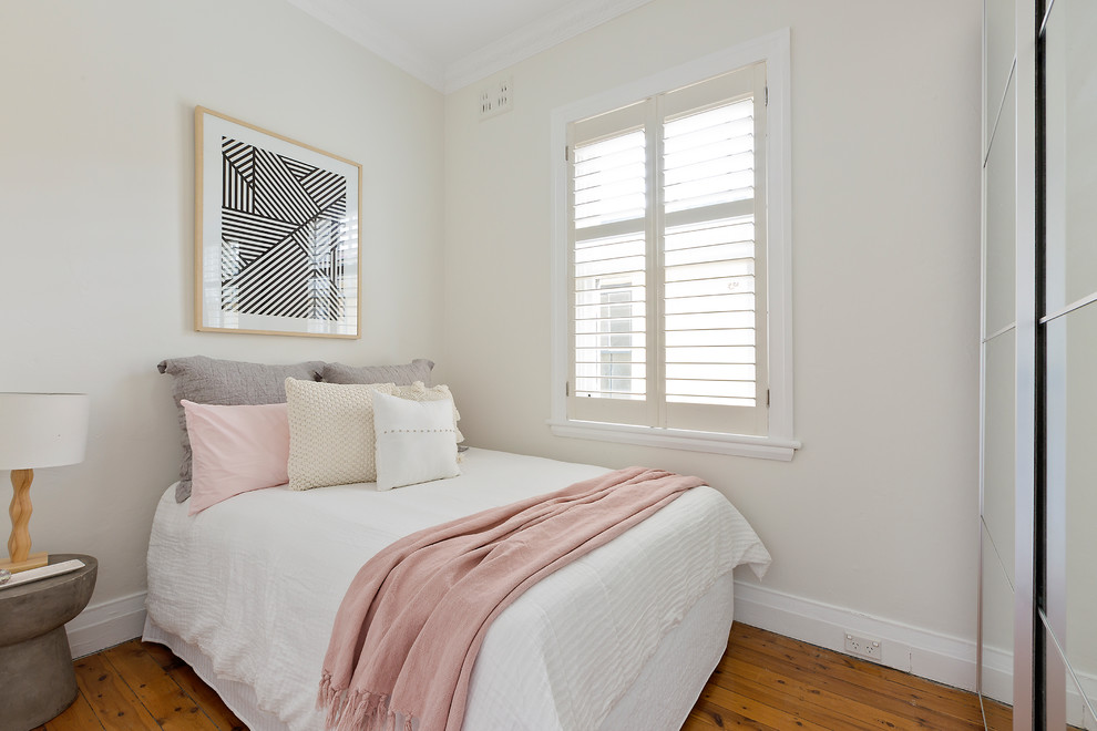 Photo of a mid-sized transitional guest bedroom in Sydney with medium hardwood floors, beige walls and brown floor.