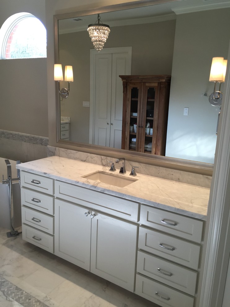 This is an example of a large modern master bathroom in Dallas with an undermount sink, shaker cabinets, white cabinets, marble benchtops, a freestanding tub, a corner shower, a one-piece toilet, white tile, stone tile, white walls and marble floors.
