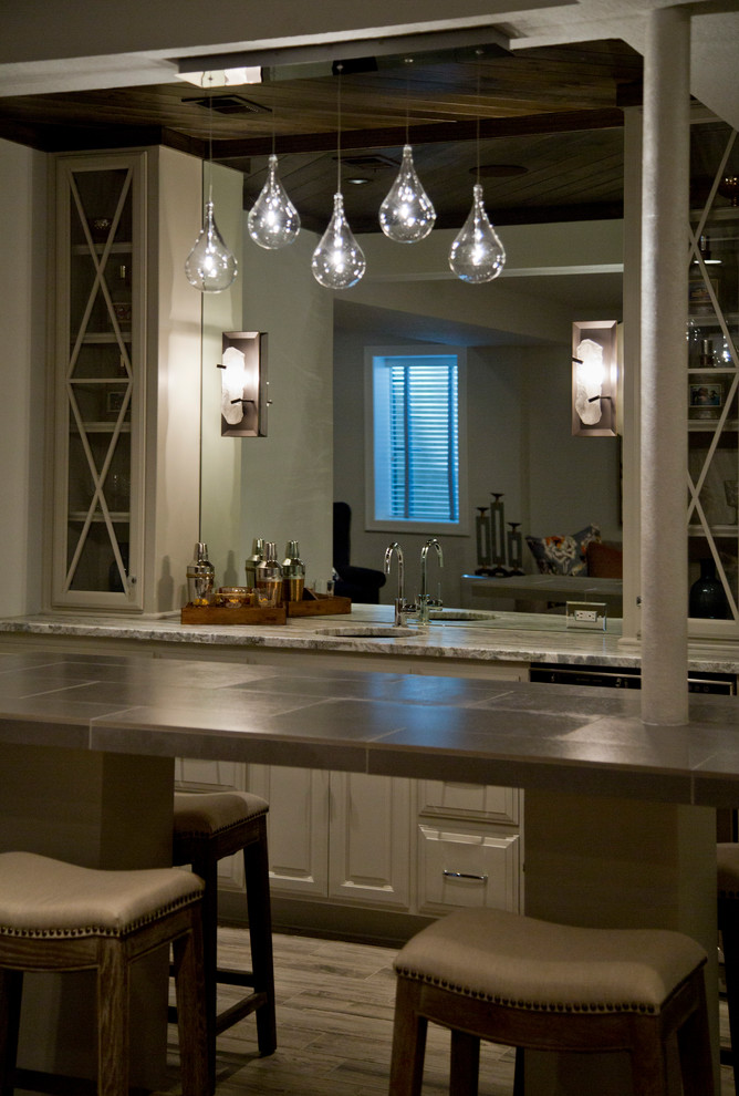 Inspiration for a large contemporary galley seated home bar in Kansas City with an undermount sink, raised-panel cabinets, beige cabinets, tile benchtops, mirror splashback, medium hardwood floors and brown floor.