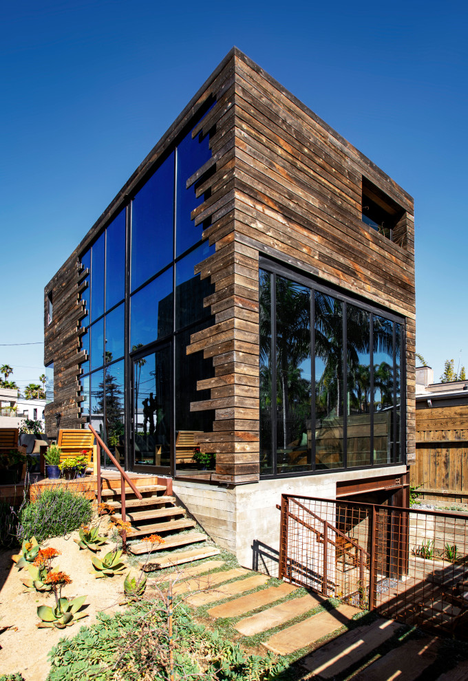 Design ideas for a mid-sized industrial two-storey brown house exterior in Los Angeles with wood siding, a shed roof, clapboard siding and a brown roof.