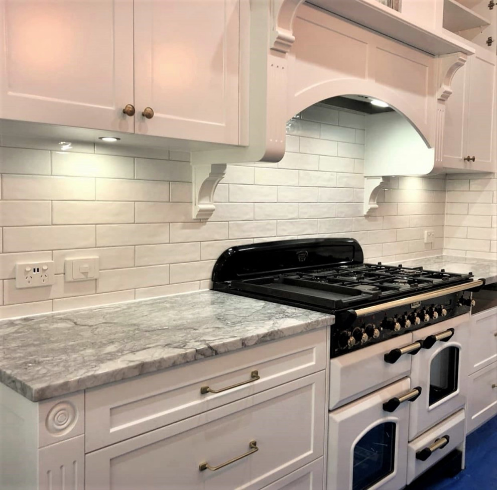 Inspiration for a mid-sized traditional kitchen pantry in Brisbane with a drop-in sink, shaker cabinets, white cabinets, granite benchtops, white splashback, subway tile splashback, white appliances, with island and grey benchtop.