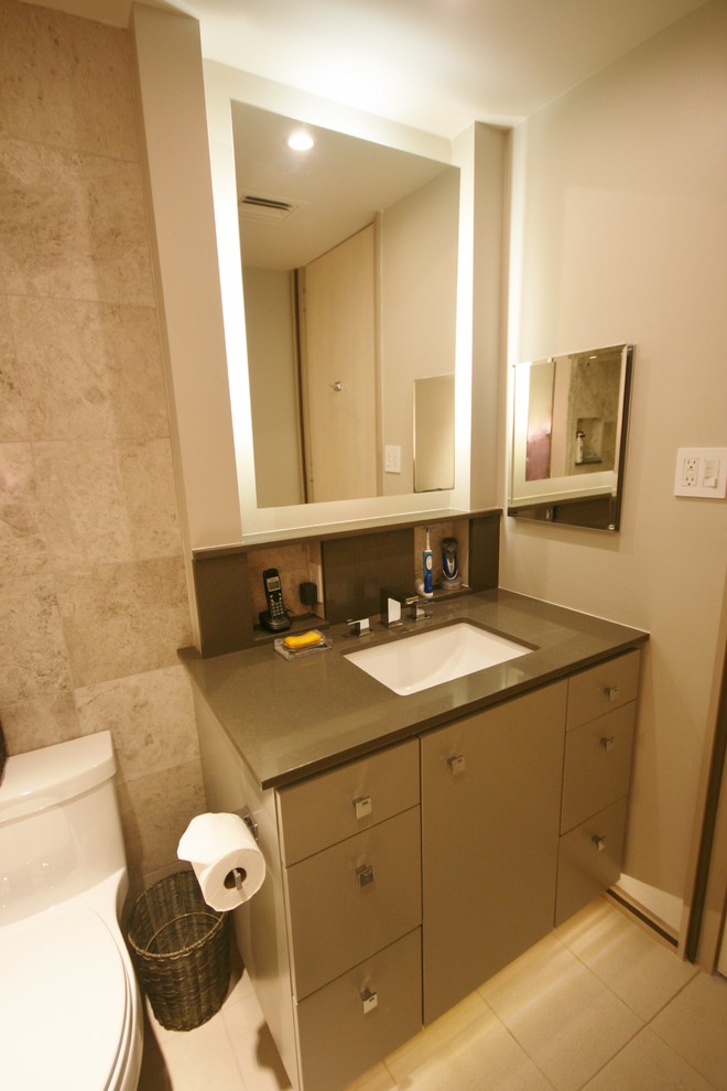 This is an example of a modern bathroom in Houston with an undermount sink, flat-panel cabinets, grey cabinets, engineered quartz benchtops, a shower/bathtub combo, a one-piece toilet, gray tile and stone tile.