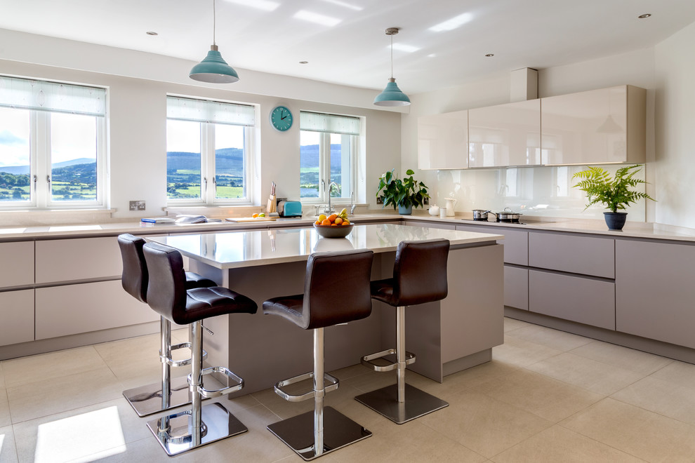 Large contemporary l-shaped kitchen in Dublin with flat-panel cabinets, quartzite benchtops, glass sheet splashback, panelled appliances, porcelain floors, with island, white splashback, an undermount sink and beige floor.