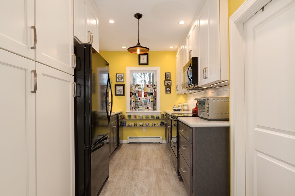 Small midcentury galley eat-in kitchen in Providence with a drop-in sink, flat-panel cabinets, white cabinets, laminate benchtops, white splashback, subway tile splashback, black appliances, vinyl floors, no island and grey floor.