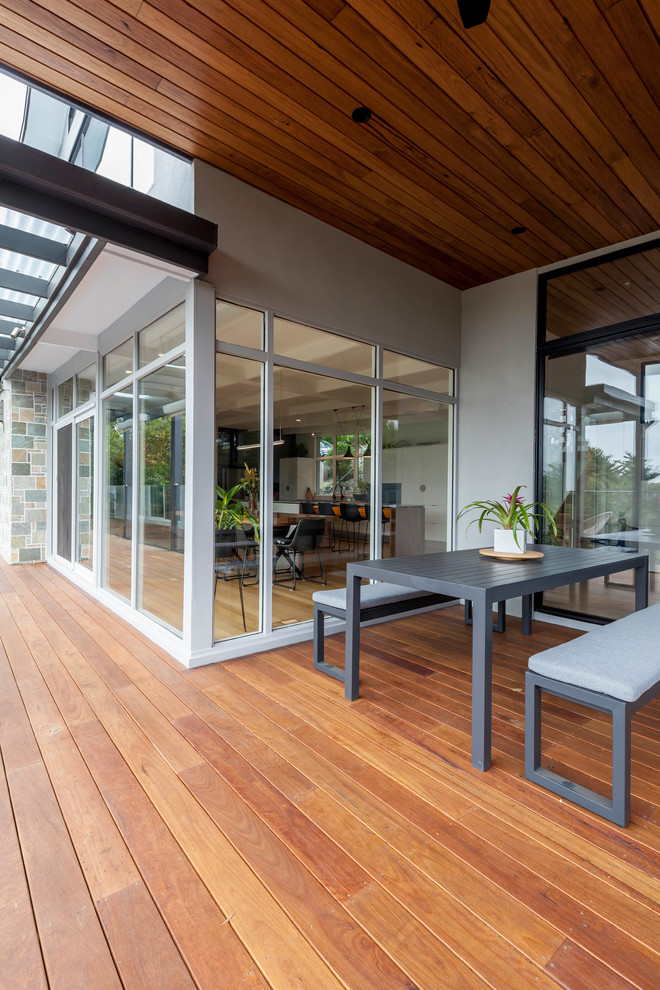Inspiration for a large midcentury backyard deck in Melbourne with a roof extension.
