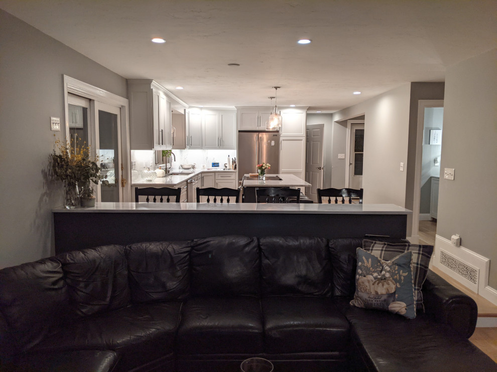 Example of a huge transitional l-shaped light wood floor eat-in kitchen design in Boston with an undermount sink, shaker cabinets, white cabinets, granite countertops, white backsplash, granite backsplash, stainless steel appliances, an island and white countertops