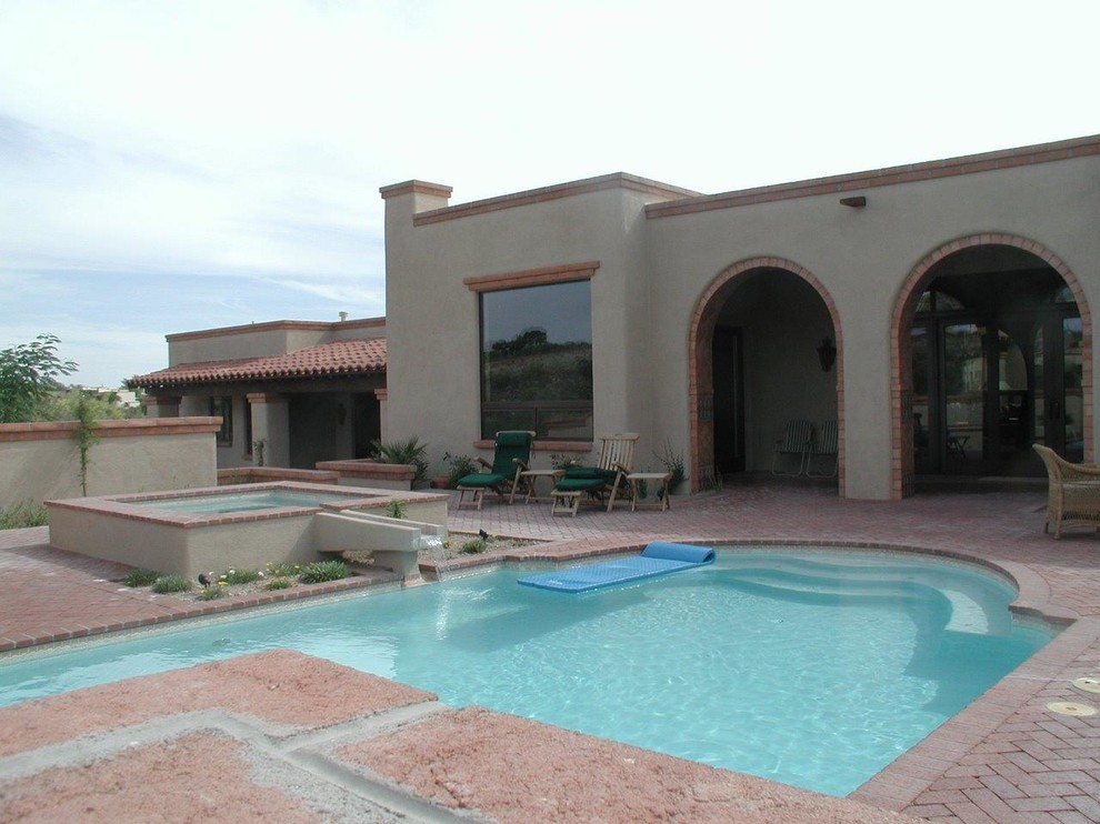 Large backyard brick and custom-shaped lap hot tub photo in Phoenix