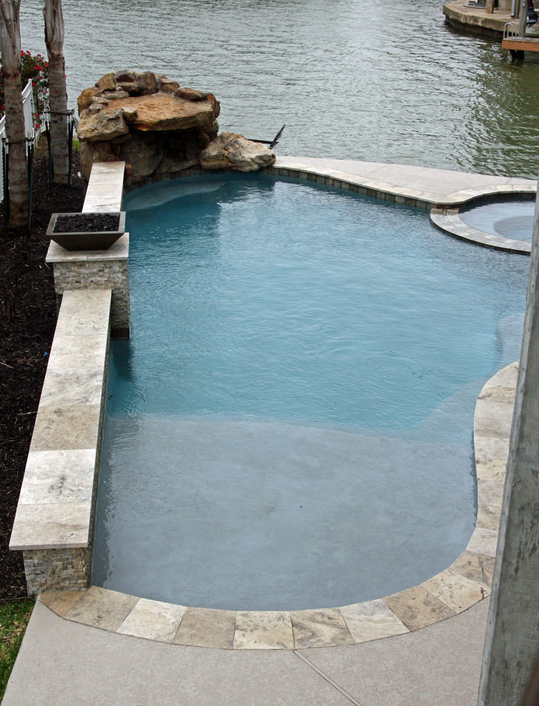 Small traditional side yard custom-shaped natural pool in Houston with a hot tub and natural stone pavers.