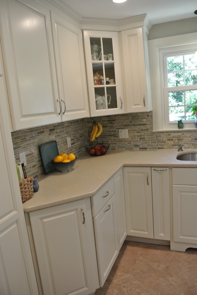 Example of a transitional u-shaped porcelain tile and beige floor kitchen design in Boston with an undermount sink, raised-panel cabinets, white cabinets, beige backsplash, subway tile backsplash and stainless steel appliances