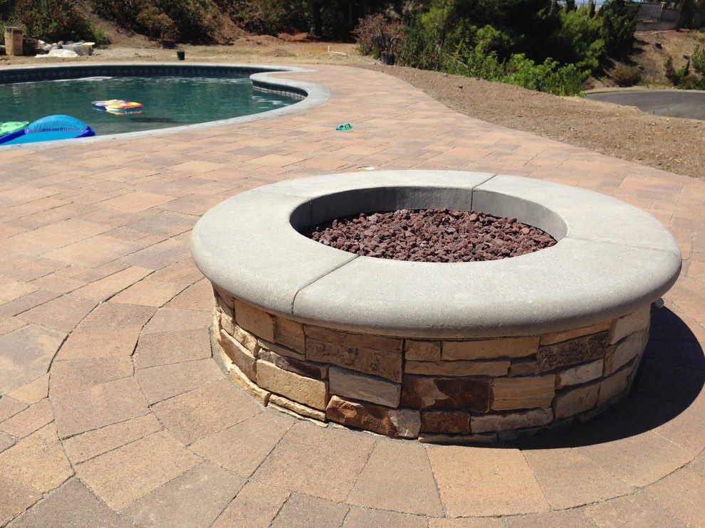This is an example of a large contemporary backyard custom-shaped lap pool in Orange County with a hot tub and concrete pavers.