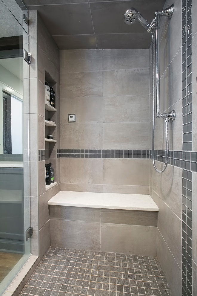 This is an example of a large transitional master bathroom in Minneapolis with shaker cabinets, grey cabinets, a freestanding tub, a corner shower, gray tile, porcelain tile, grey walls, medium hardwood floors, an undermount sink, engineered quartz benchtops, brown floor, a hinged shower door and white benchtops.