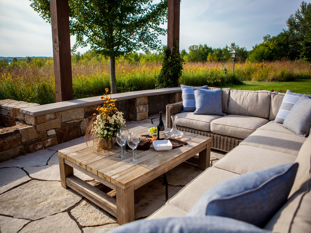 Patio - large rustic backyard stone patio idea in Minneapolis with a pergola