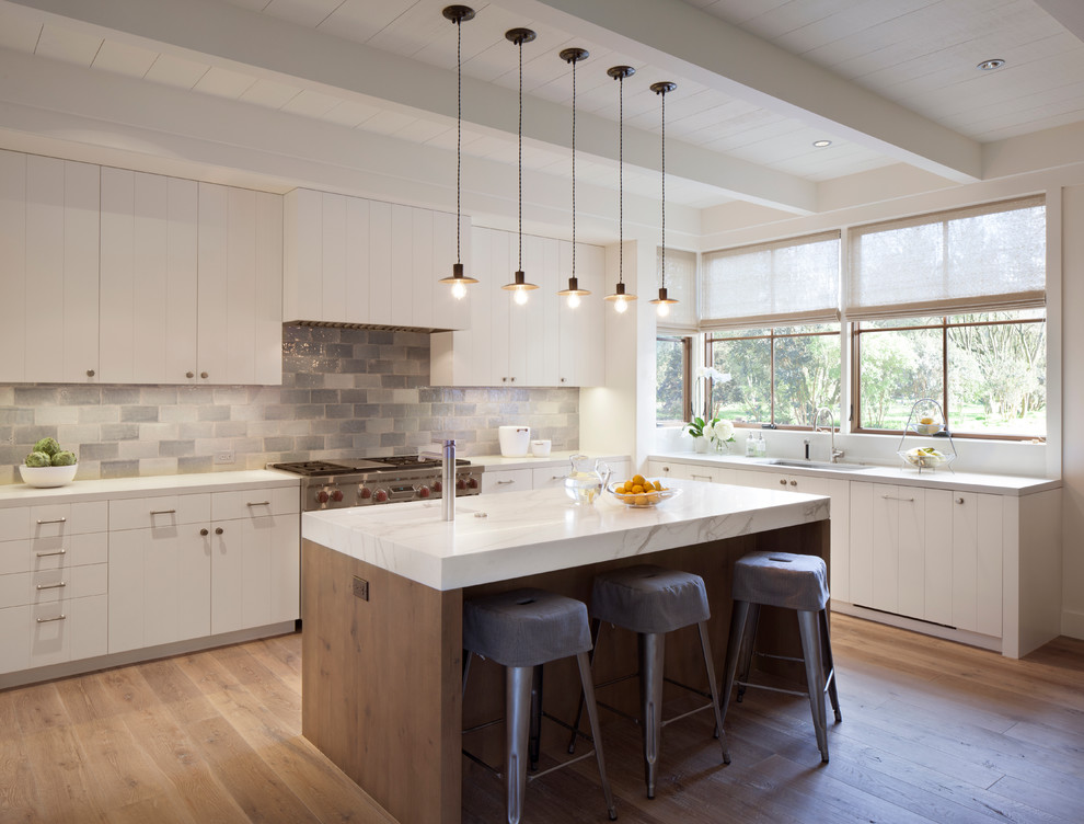 Inspiration for a country l-shaped kitchen in San Francisco with an undermount sink, white cabinets, multi-coloured splashback, mosaic tile splashback, stainless steel appliances, light hardwood floors and with island.