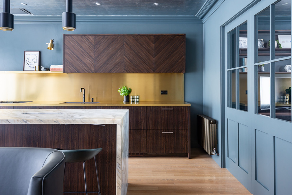 Mid-sized midcentury galley eat-in kitchen in London with an integrated sink, flat-panel cabinets, dark wood cabinets, marble benchtops, metallic splashback, stainless steel appliances, medium hardwood floors, with island, brown floor and white benchtop.
