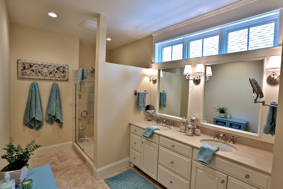 Design ideas for a mid-sized traditional master bathroom in Chicago with an undermount sink, raised-panel cabinets, white cabinets, solid surface benchtops, an alcove shower, a two-piece toilet, beige tile, stone tile, beige walls and porcelain floors.