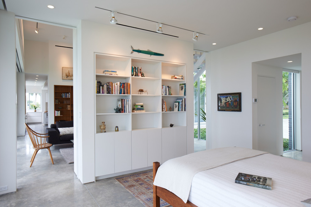 Modern bedroom in Other with concrete floors, white walls and grey floor.